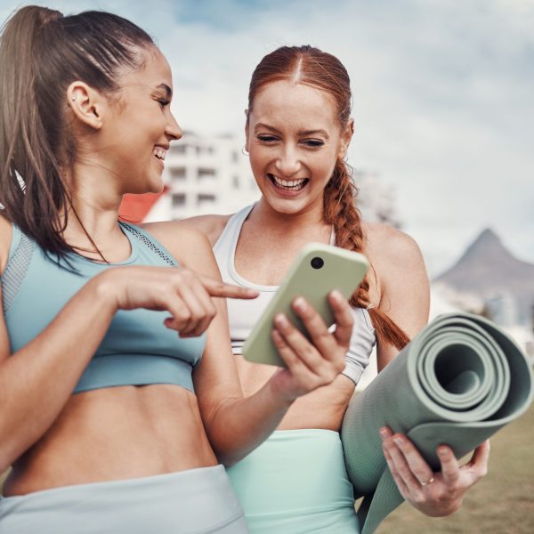 Yoga, fitness and social media with woman friends in the park together for mental health exercise. Exercise, phone and training with a female and friend outside on a grass field for a summer workout.