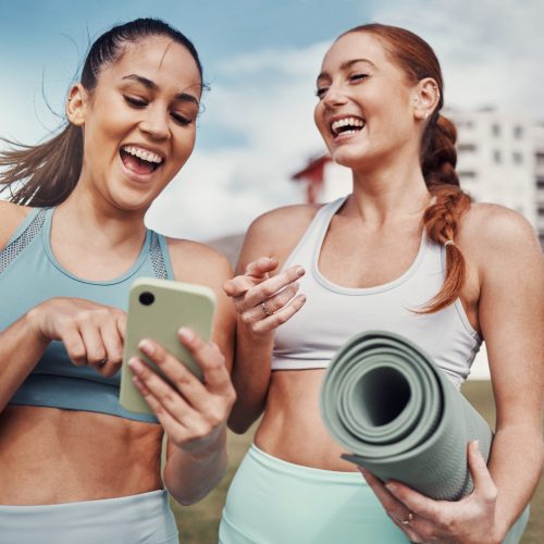 Yoga, fitness and phone with woman friends laughing at a meme in the park together during exercise. Pilates, social media and training with a female and friend joking outside on a field for a workout.