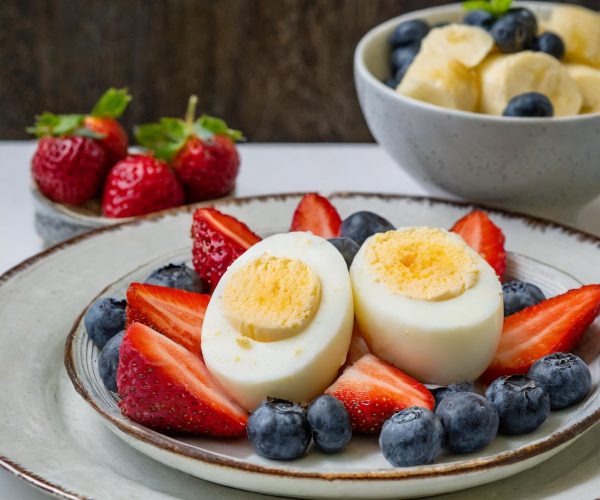 Firefly Two Boiled Eggs on a plate with a small bowl of Mixed Fruit Salad_ made of cliced bananas, s