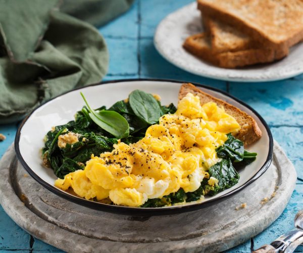 Firefly scrambled eggs with spinach and whole wheat toast on a blue tile background 78709