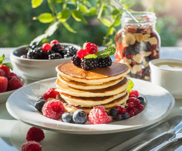 Firefly small stack Protein Pancakes with a Side of Mixed Berries at a sunny modern breakfast table